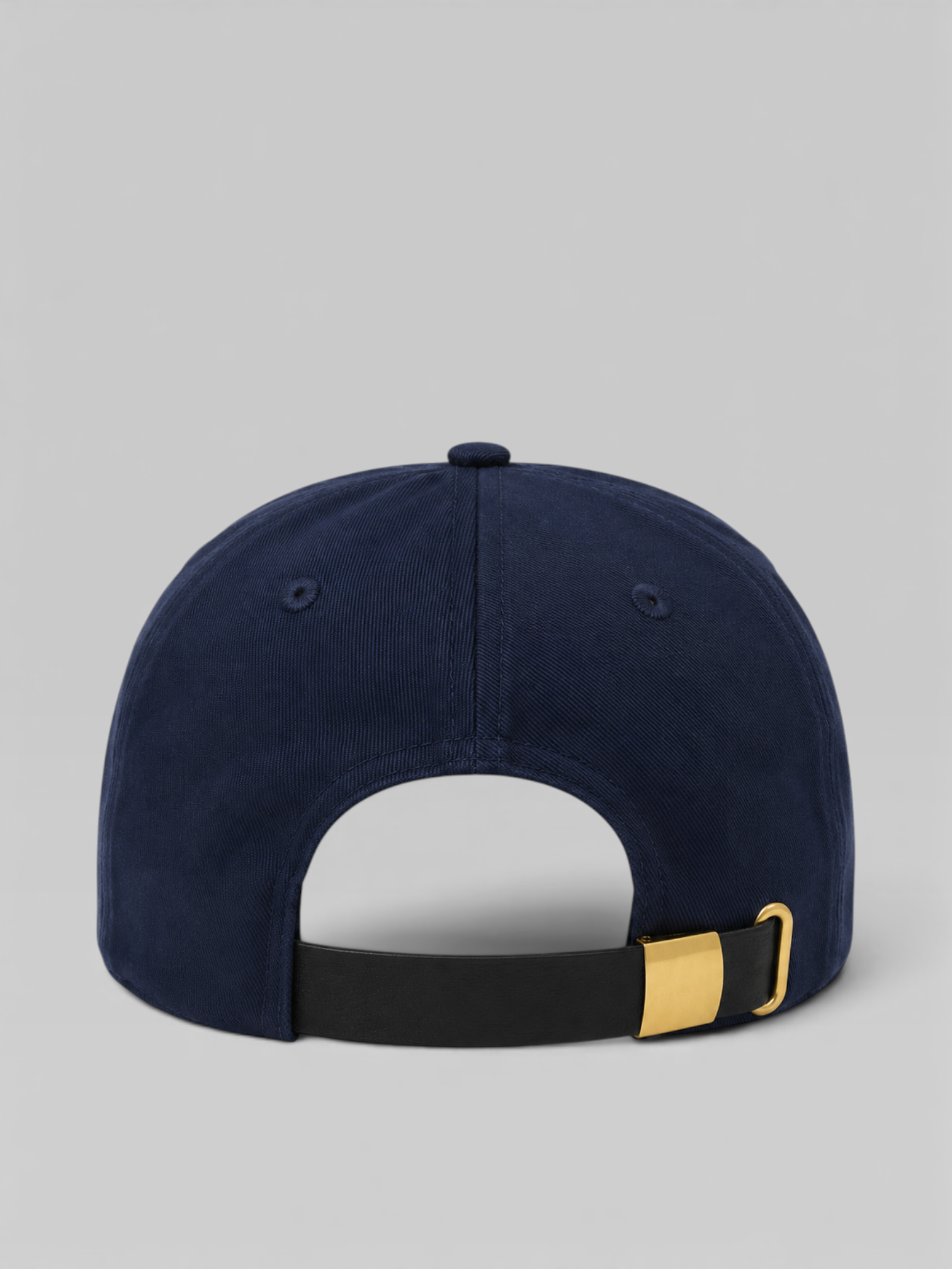 Navy blue cap with a gold buckle & leather strap on a gray background
